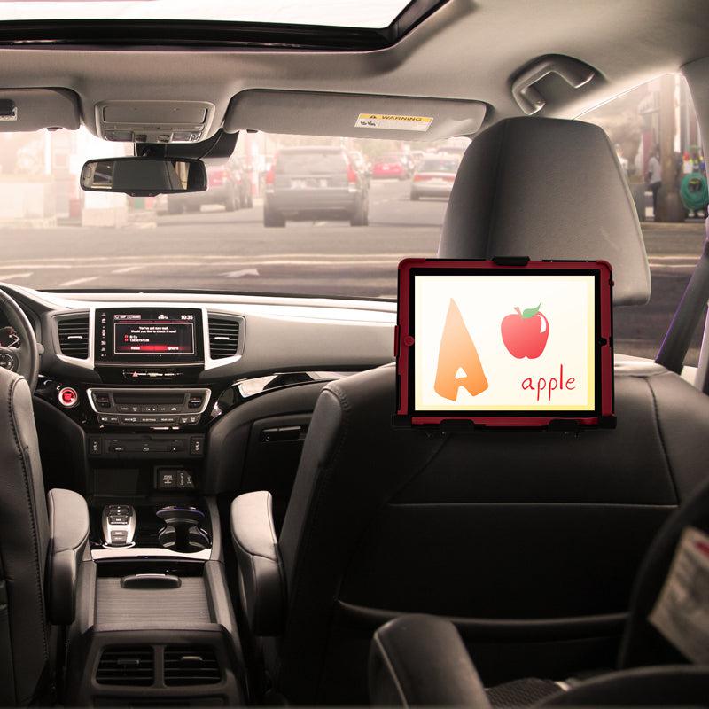 A tablet mounted on a LockVise™ Metal Locking Car Headrest Tablet Mount shows the letter A and an apple image with apple. The parked car’s backseat view includes the dashboard and sunroof.