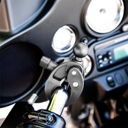 Close-up of the Robust™ Mount Clamp Post with 25mm (1) Ball secured to a shiny metal bar on a motorcycle, with dashboard gauges and radio blurred in the background.