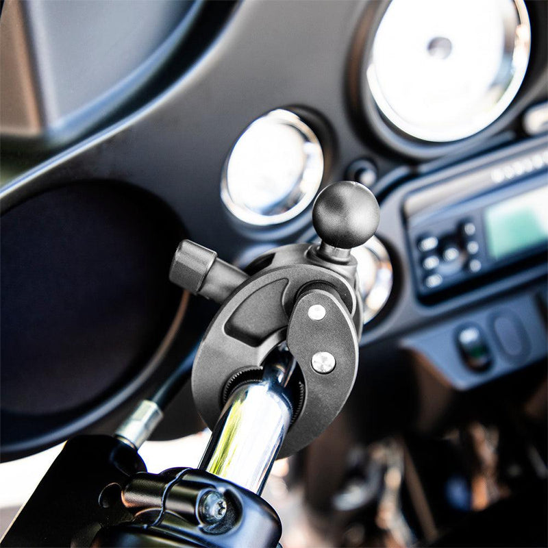 Close-up of the Robust™ Mount Clamp Post with 25mm (1) Ball secured to a shiny metal bar on a motorcycle, with dashboard gauges and radio blurred in the background.