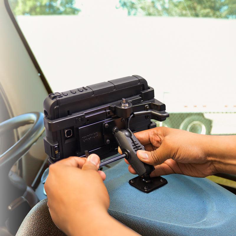 A person installs a rugged tablet using the Security Kit for 25mm Ball Compatible Shaft onto a mounting bracket by the driver’s seat, ensuring secure and stable placement for reliable in-vehicle use.