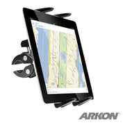 The Slim-Grip® Tablet Clamp Mount for Stationary Bicycle, Treadmill, Elliptical, and Spin Bike firmly holds a tablet showing a map on a clamp attached to a surface. The Arkon logo is featured in the bottom right corner.