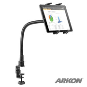 A Slim-Grip® Tablet Holder with Clamp Mount and 22 Gooseneck is attached to a surface, securely holding a tablet displaying charts. The ARKON logo appears in the bottom right corner.