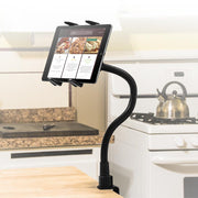 The Slim-Grip® Tablet Holder with Clamp Mount and 22 Gooseneck is clamped to the kitchen counter, securely displaying recipes on a tablet, with a stove, kettle, and other appliances visible in the background.