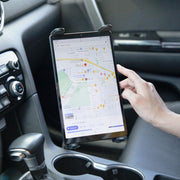 Using the Slim-Grip® Tablet Holder with Seat Rail Mount and 22 Bendable Arm, a person secures their tablet in the car to view navigation apps, with the dashboard and gear shift also visible.