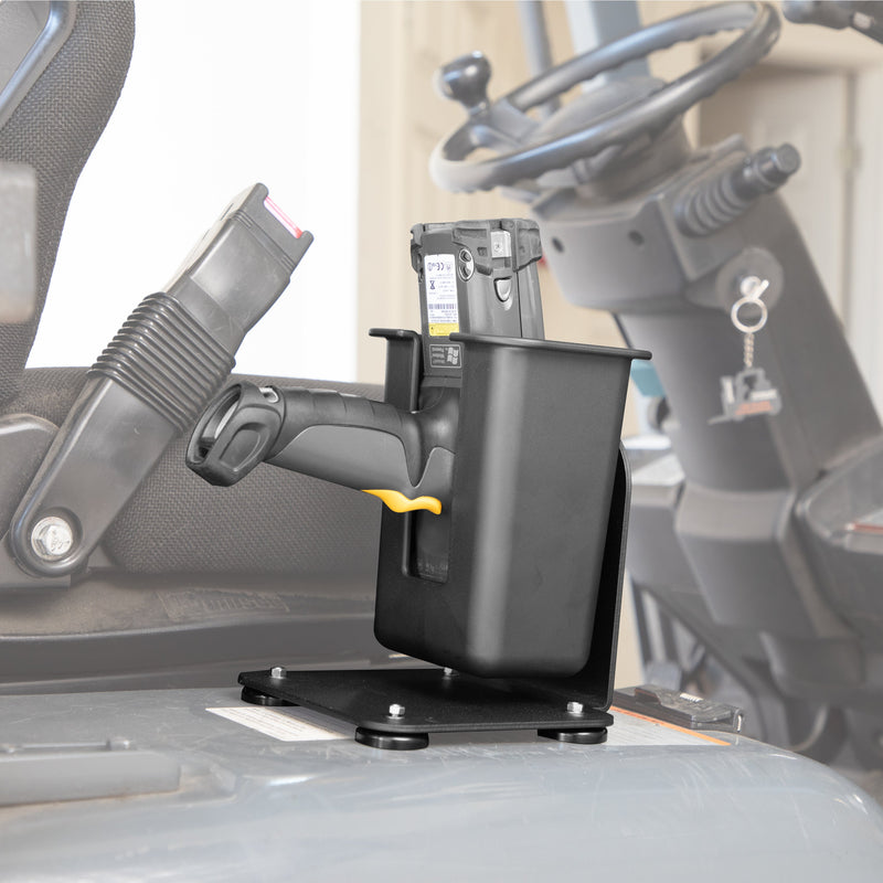 A SteadyMag™ Magnetic Mount System with Large Barcode Scanner Holder secures a black handheld barcode scanner in its charging cradle, with a seatbelt and steering wheel visible in the blurred background.