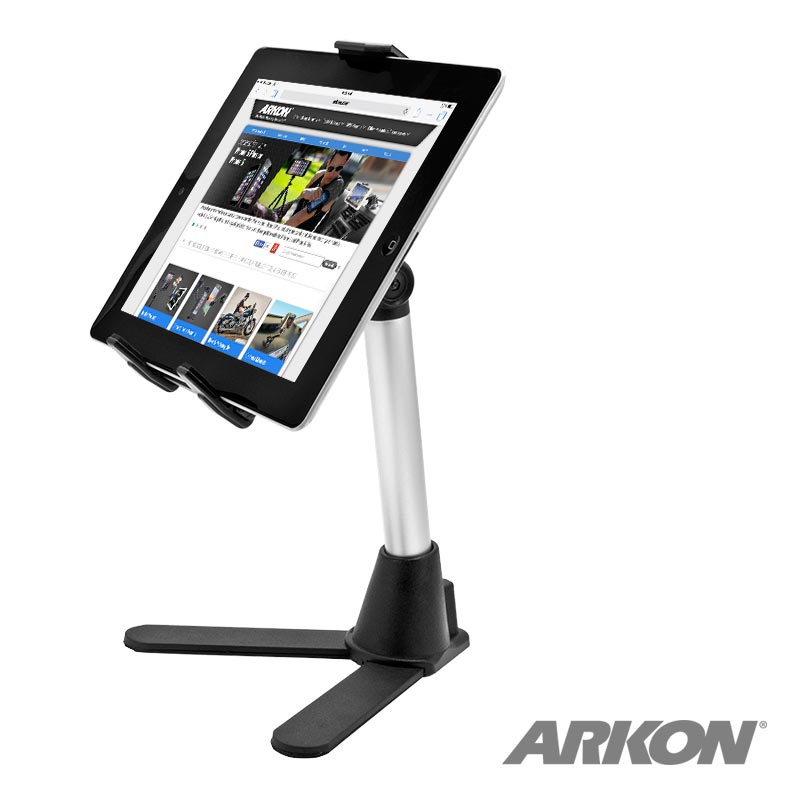 A tablet is shown on a silver and black Desk Stand Mount with Tablet Holder, featuring a sturdy wide base. The tablet displays a website, making the stand ideal for teaching. “ARKON” appears in the lower right corner.