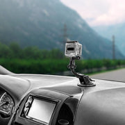A GoPro HERO Action Camera Holder with Suction Mount and Adhesive Disk is fixed to the dashboard, capturing a blurred view of mountains and greenery through the windshield.