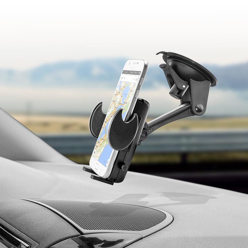 An iPhone in the Windshield or Dash Mega Grip™ Phone Car Holder Mount is attached to a vehicle dashboard with a suction cup, displaying a map, with a blurred road and landscape visible through the windshield.