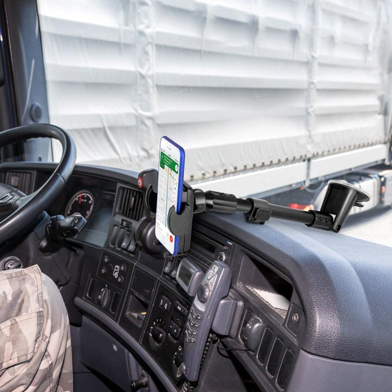 A smartphone is held by the Windshield Suction Car Mega Grip™ Phone Mount with an extendable arm on a truck dashboard, displaying GPS directions. A person in camouflage pants sits in the driver’s seat, with the steering wheel and controls visible.